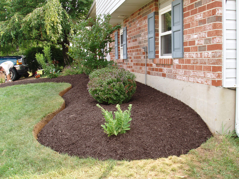 Newly landscaped garden bed in front of a brick house