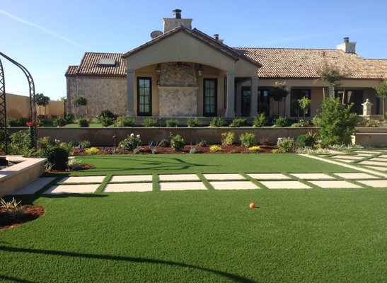 Lush green lawn in front of a stone building with a clear blue sky.